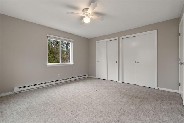 unfurnished bedroom featuring a baseboard heating unit, ceiling fan, two closets, and light colored carpet