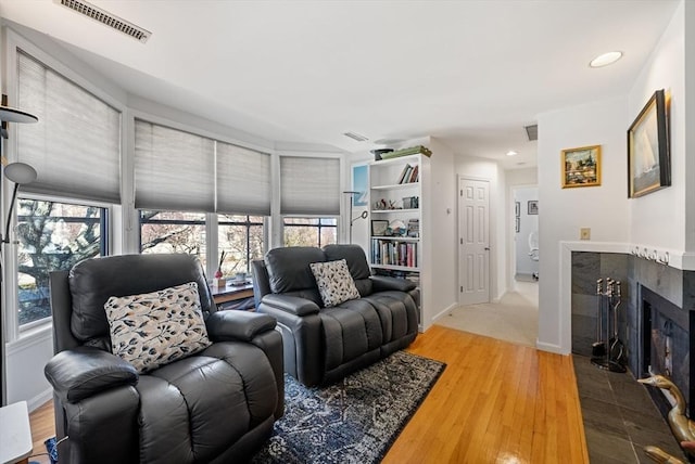 living room with visible vents, wood finished floors, recessed lighting, baseboards, and a tile fireplace