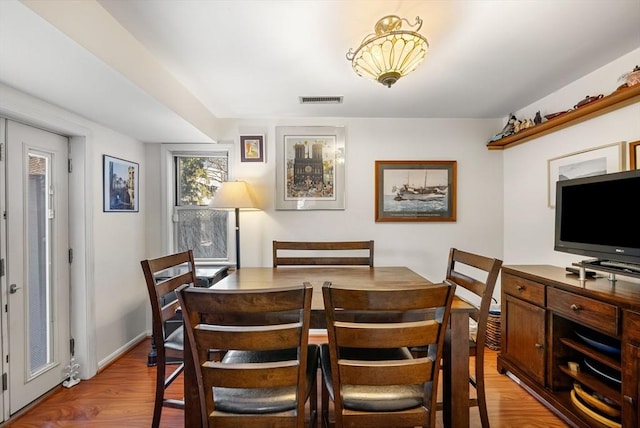 dining room featuring baseboards, visible vents, and light wood finished floors