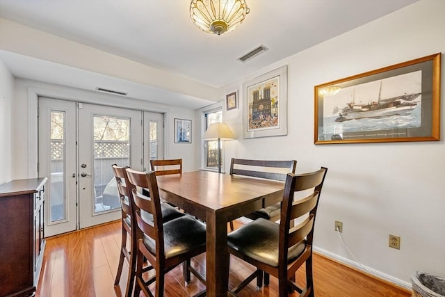 dining area with baseboards, visible vents, and light wood finished floors