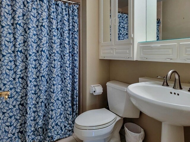 full bath featuring toilet, a shower with curtain, a sink, and tile patterned flooring