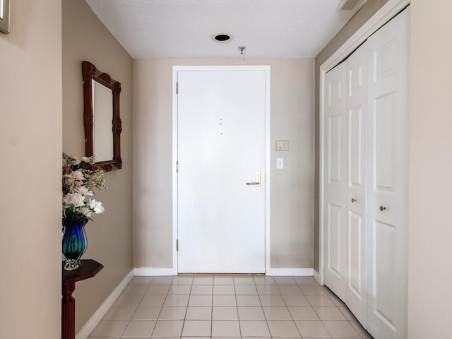 interior space with light tile patterned floors, baseboards, and a textured ceiling