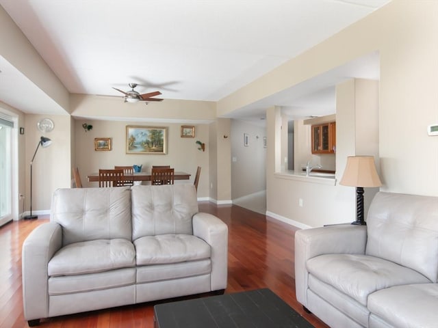 living room with a ceiling fan, baseboards, and wood finished floors