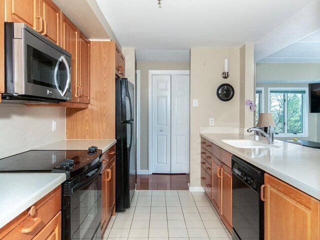 kitchen with light countertops, brown cabinets, a sink, and black appliances