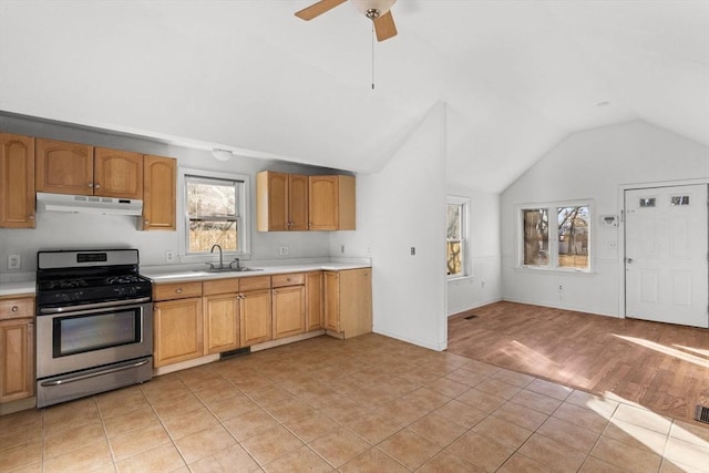 kitchen with under cabinet range hood, light countertops, vaulted ceiling, gas stove, and a sink