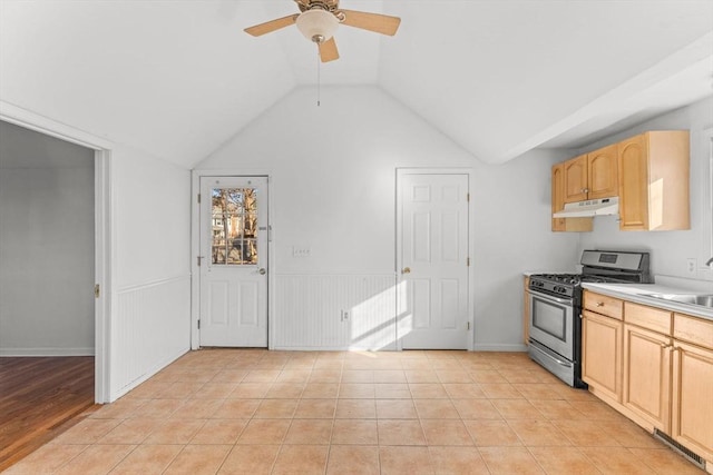 kitchen featuring light tile patterned floors, stainless steel range with gas stovetop, light brown cabinetry, light countertops, and under cabinet range hood