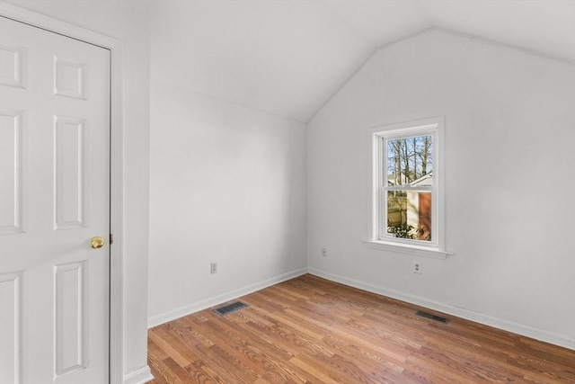 interior space with lofted ceiling, wood finished floors, visible vents, and baseboards