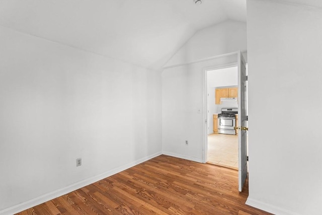 unfurnished room featuring baseboards, wood finished floors, and vaulted ceiling