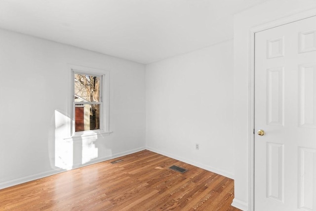 spare room featuring visible vents, baseboards, and wood finished floors