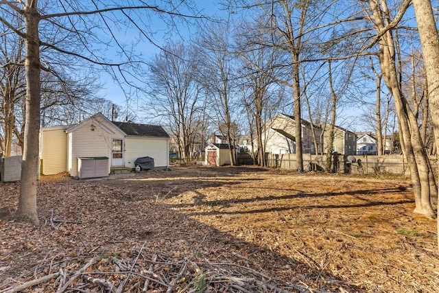 view of yard featuring a storage shed, fence, and an outdoor structure