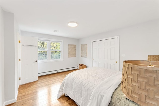 bedroom with a baseboard heating unit and light wood finished floors