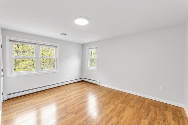 spare room featuring a baseboard radiator, light wood finished floors, and baseboards