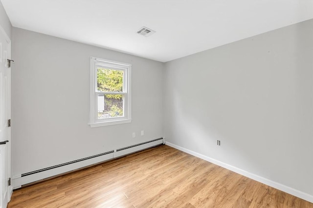 unfurnished room featuring baseboard heating, light wood-type flooring, and baseboards