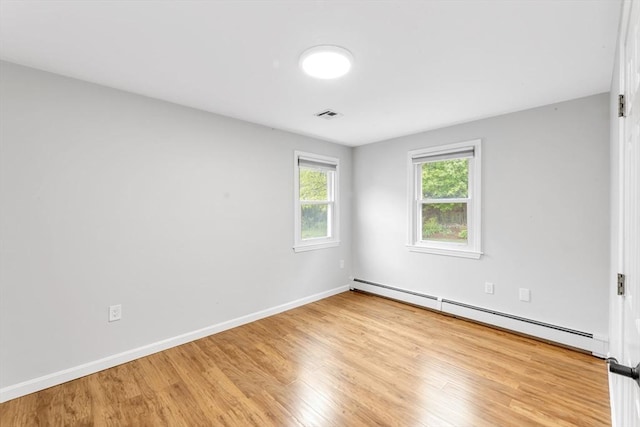 empty room with a baseboard radiator, wood finished floors, and baseboards