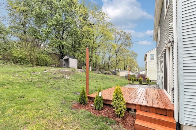 view of green lawn with a shed, an outbuilding, and a deck