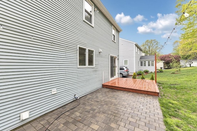 rear view of house featuring a patio, a deck, and a lawn