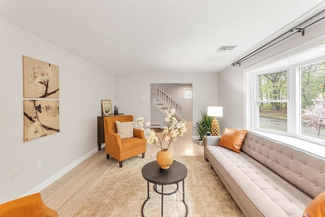living room with stairway, light wood-type flooring, and baseboards