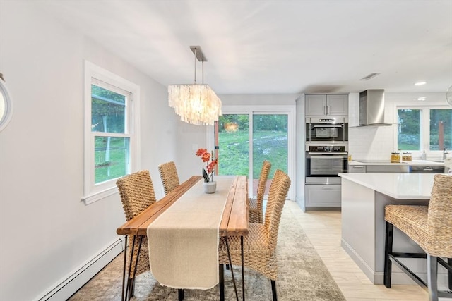 dining space featuring a baseboard radiator, a chandelier, light wood-type flooring, and baseboards