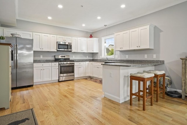5 Mackenzie Way Unit 5, Haverhill, MA 01832 - kitchen with stainless steel appliances, a peninsula, ornamental molding, white cabinets, and light wood-type flooring