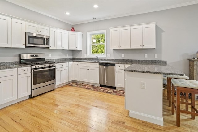 5 Mackenzie Way Unit 5, Haverhill, MA 01832 - kitchen featuring appliances with stainless steel finishes, a peninsula, a breakfast bar area, crown molding, and light wood-style floors