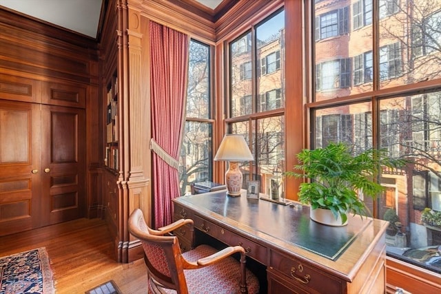 office space with wood walls, light hardwood / wood-style floors, and crown molding