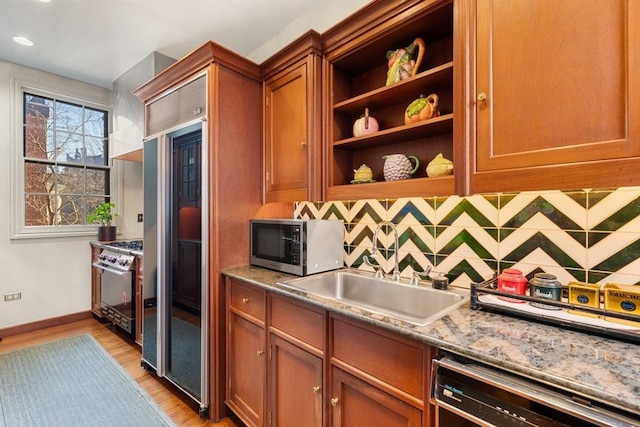 kitchen featuring light stone countertops, sink, tasteful backsplash, light hardwood / wood-style floors, and high end appliances