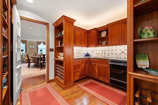 bar with dishwasher, light wood-type flooring, tasteful backsplash, and sink