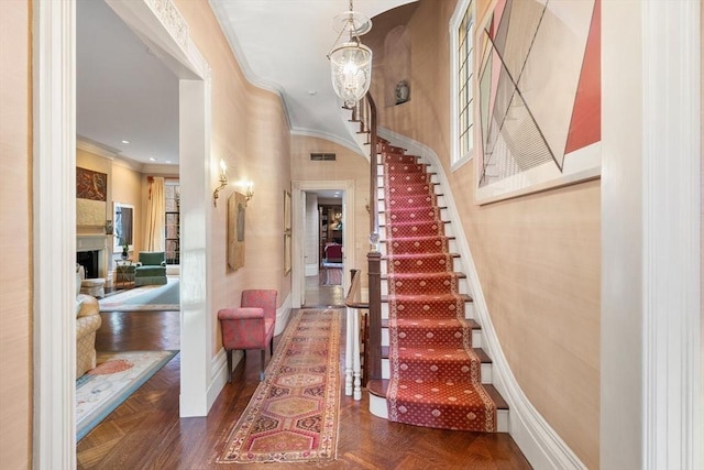 interior space with dark parquet floors, an inviting chandelier, and ornamental molding