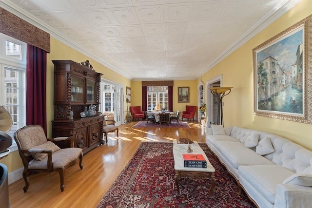 living room featuring an ornate ceiling, crown molding, and light wood-style flooring