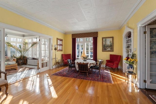 living area with ornamental molding, radiator, and wood finished floors