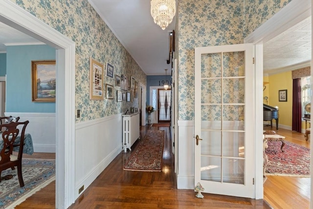 hallway with crown molding, a wainscoted wall, a notable chandelier, and wallpapered walls