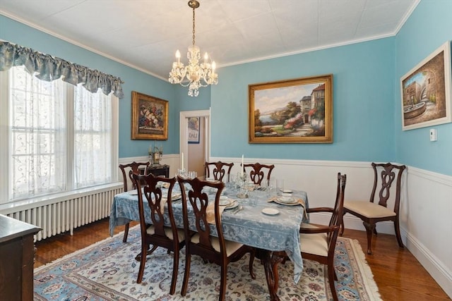 dining area with crown molding, radiator, a notable chandelier, and wood finished floors