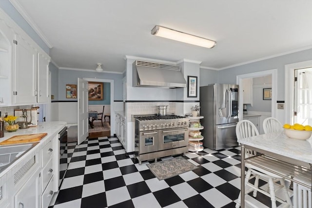 kitchen with white cabinets, dark floors, stainless steel appliances, light countertops, and wall chimney range hood