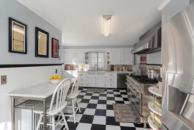 kitchen featuring dark floors, appliances with stainless steel finishes, white cabinetry, a sink, and ventilation hood