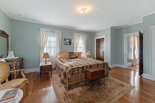 bedroom with ornamental molding, baseboards, and wood finished floors