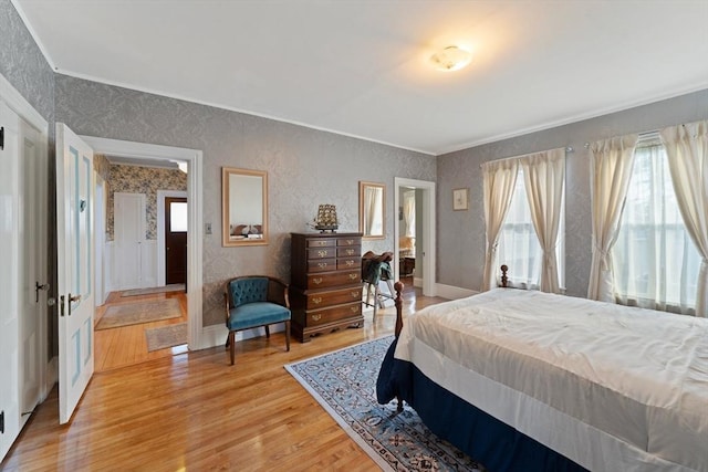 bedroom with ornamental molding, light wood-style flooring, baseboards, and wallpapered walls