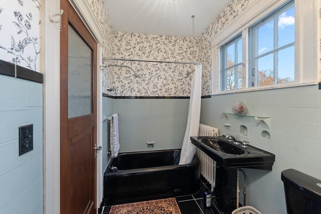 bathroom featuring wallpapered walls, shower / bath combo, tile walls, and a wainscoted wall