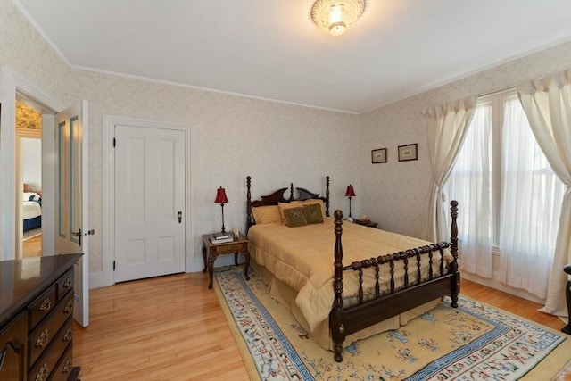 bedroom featuring wallpapered walls, light wood-style flooring, and crown molding