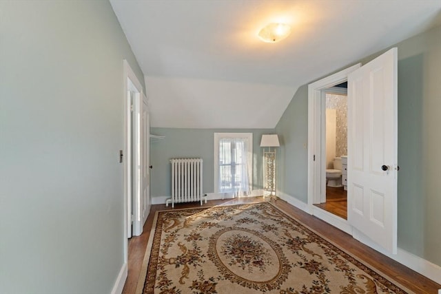 interior space with radiator heating unit, baseboards, vaulted ceiling, and wood finished floors