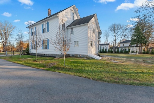 view of property exterior with a lawn and a chimney