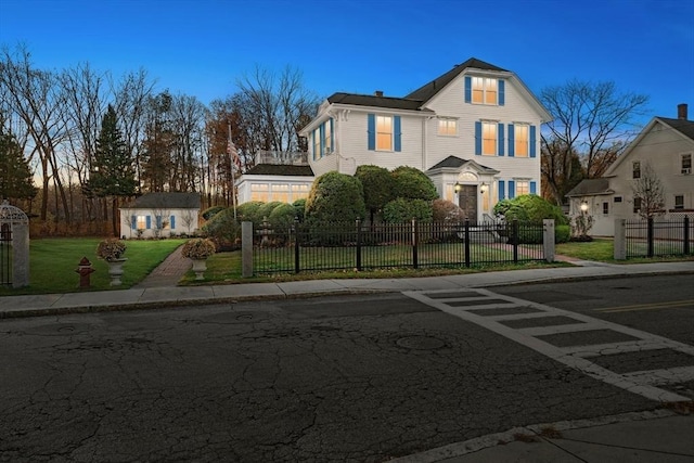 view of front facade with an outbuilding, a fenced front yard, and a front yard