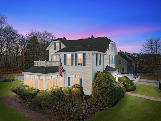 property exterior at dusk with a gambrel roof and a yard