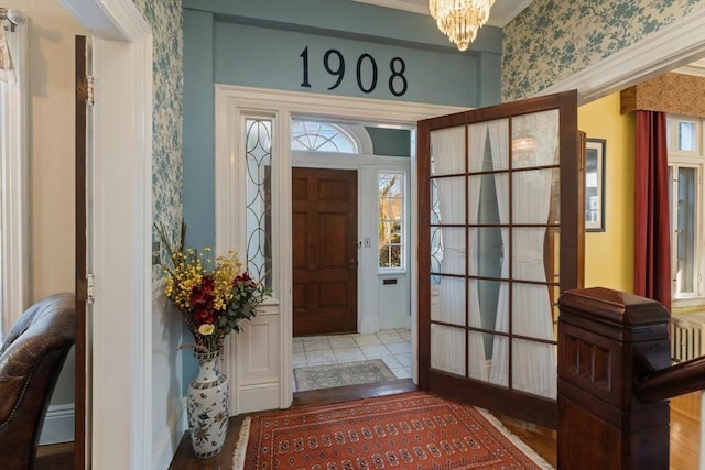 entryway with baseboards, an inviting chandelier, and wallpapered walls