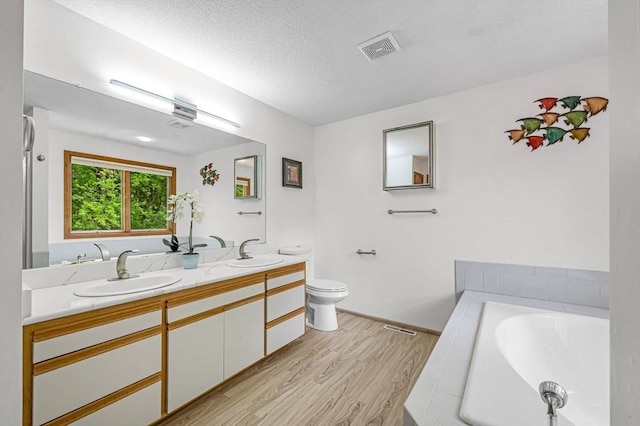 236 Williamsburg Dr, Longmeadow, MA 01106 - full bathroom with wood finished floors, double vanity, a garden tub, toilet, and a textured ceiling
