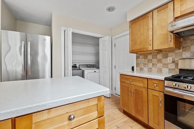 21 Nourse St, Westborough, MA 01581 - kitchen with appliances with stainless steel finishes, wall chimney range hood, washing machine and clothes dryer, backsplash, and light wood-style flooring