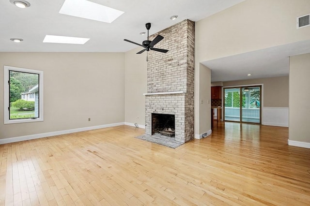 21 Nourse St, Westborough, MA 01581 - unfurnished living room with light wood-type flooring, a skylight, high vaulted ceiling, and a brick fireplace