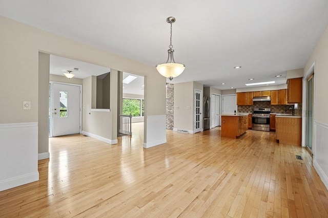 21 Nourse St, Westborough, MA 01581 - kitchen with stainless steel appliances, open floor plan, under cabinet range hood, brown cabinetry, and a sink