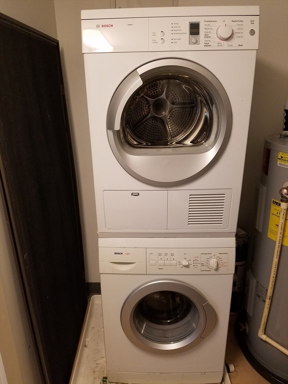 laundry area featuring electric water heater and stacked washer / dryer