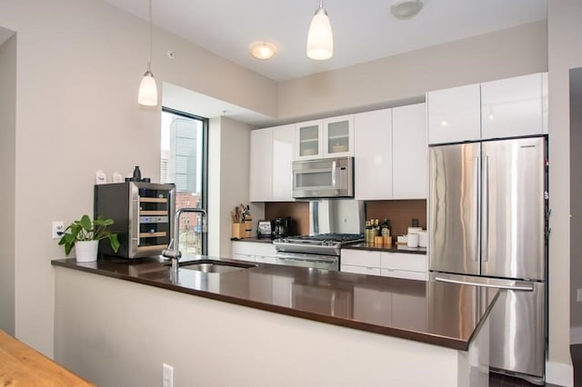 kitchen featuring sink, white cabinets, stainless steel appliances, and decorative light fixtures