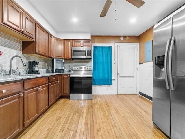 273 Elm St, Southbridge, MA 01550 - kitchen with stainless steel appliances, light wood-type flooring, brown cabinetry, a ceiling fan, and light stone counters